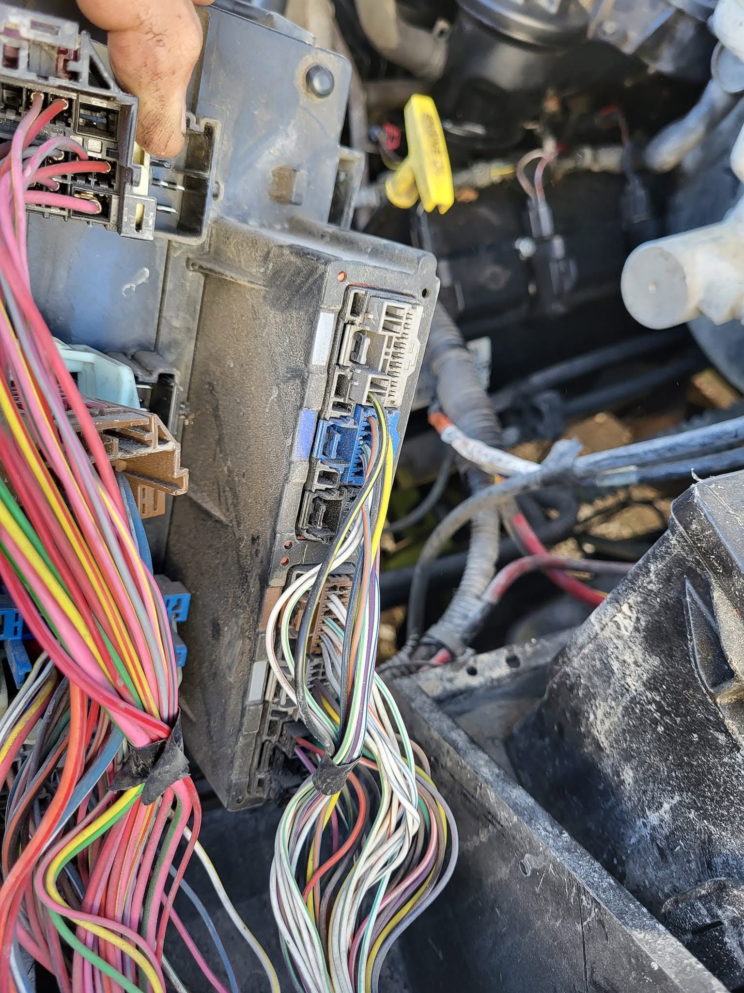 Damaged car wiring harness and fuse box with exposed multicolored wires in the engine bay