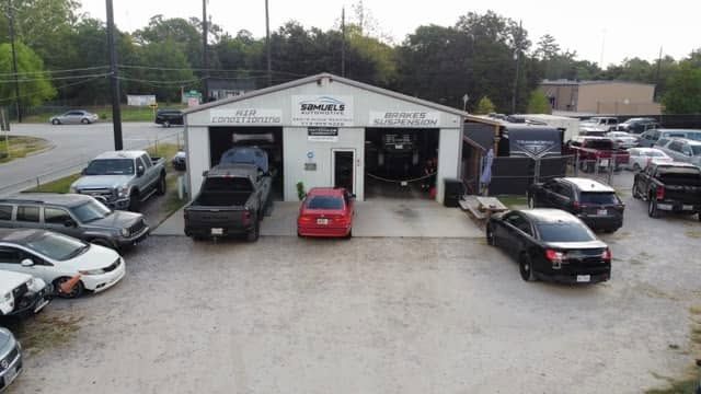 Auto repair shop front with several parked cars and open service bays