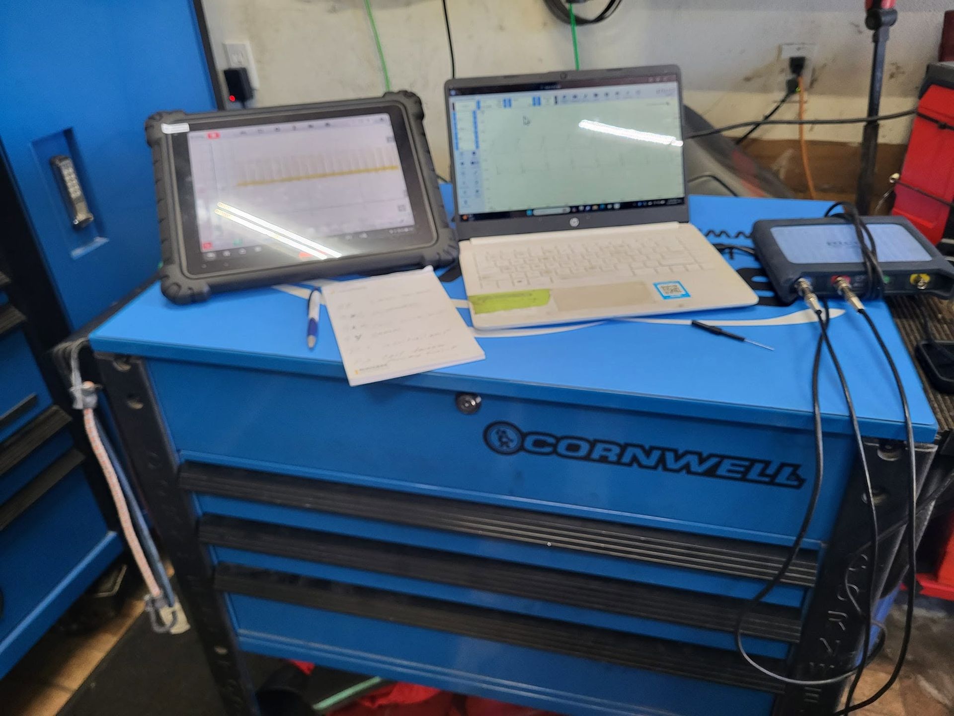 Blue Cornwell tool chest with laptop, tablet, and cables in a workshop garage