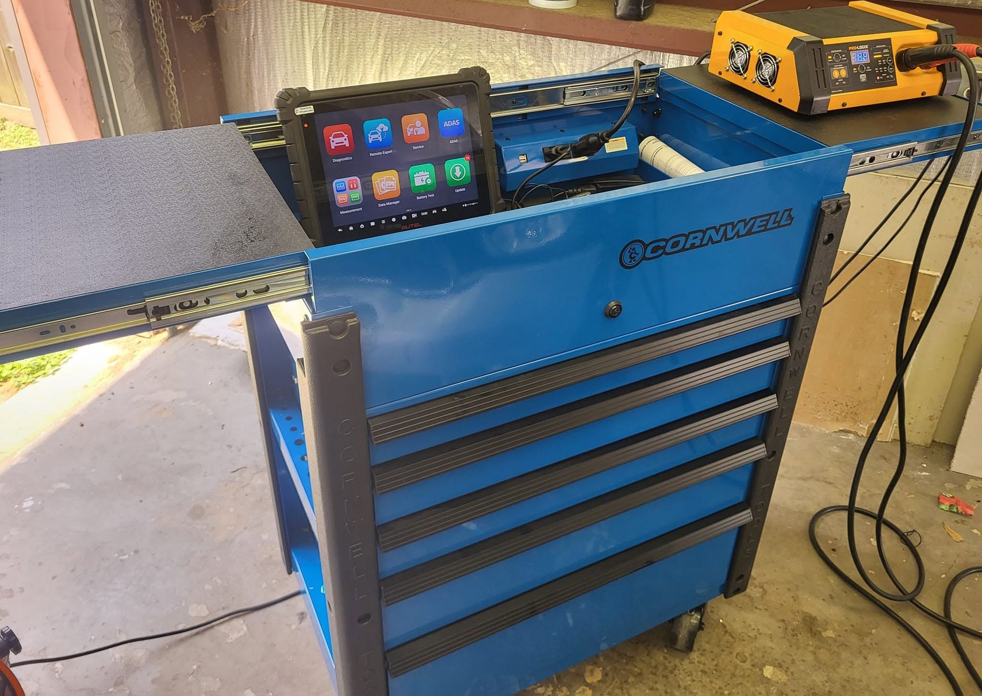 Blue rolling tool chest with drawers and a smartphone on top in a workshop garage.