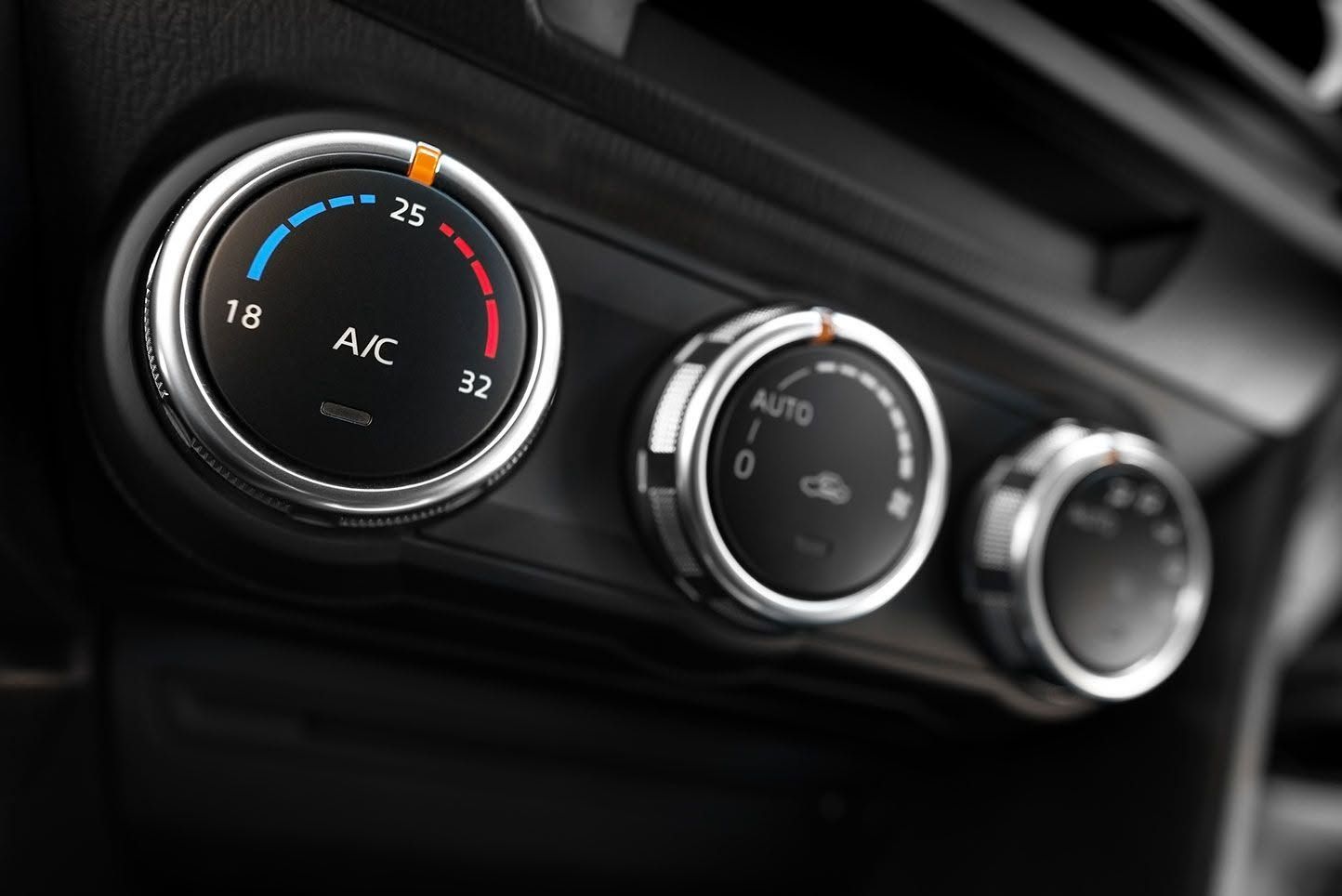 Close-up of a car dashboard climate control panel with three circular dials and blue-red temperature markings