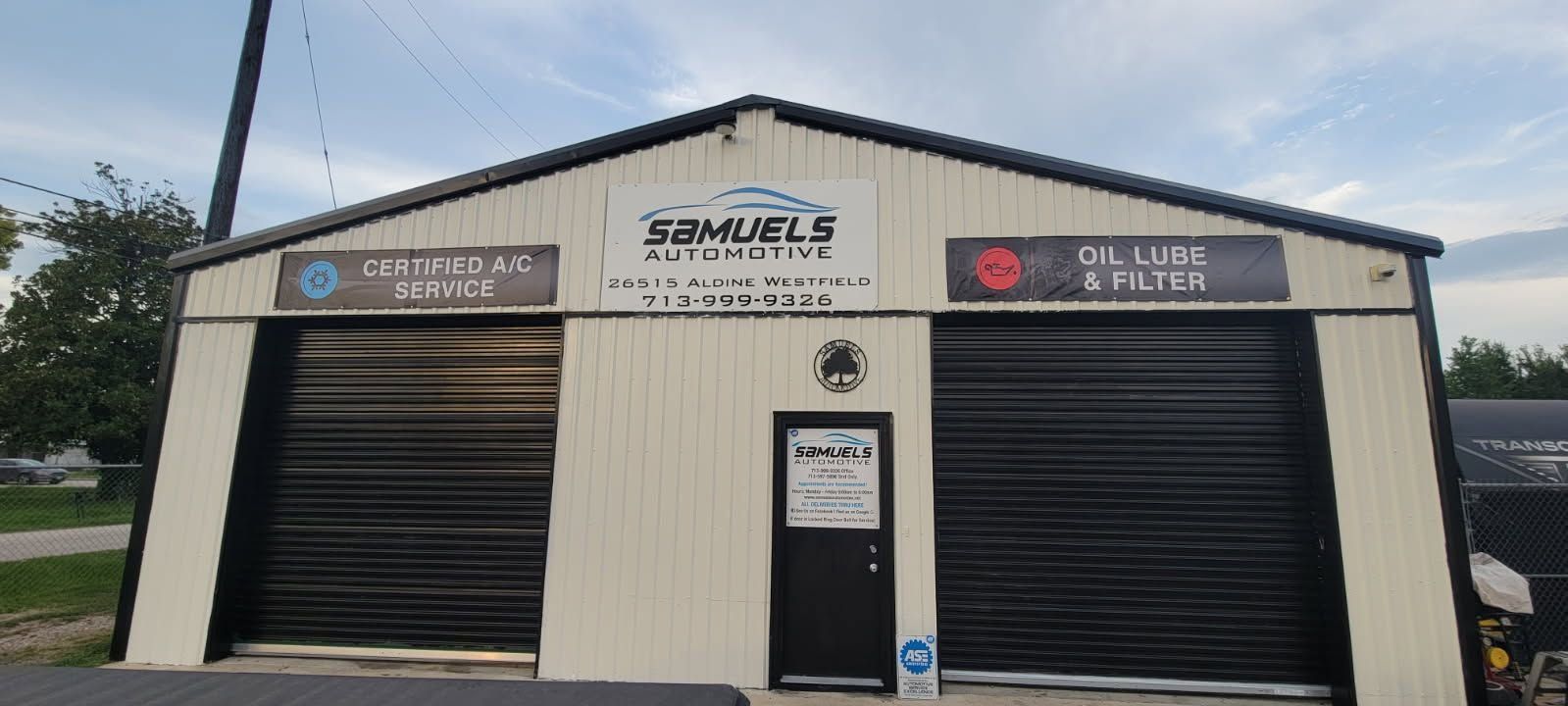 Front view of a cream metal storage building with black roll-up doors and central entrance.