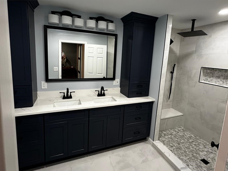 A bathroom with two sinks, a large mirror, and a walk-in shower.