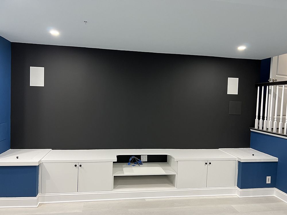 A living room with blue walls and white cabinets and a black wall.