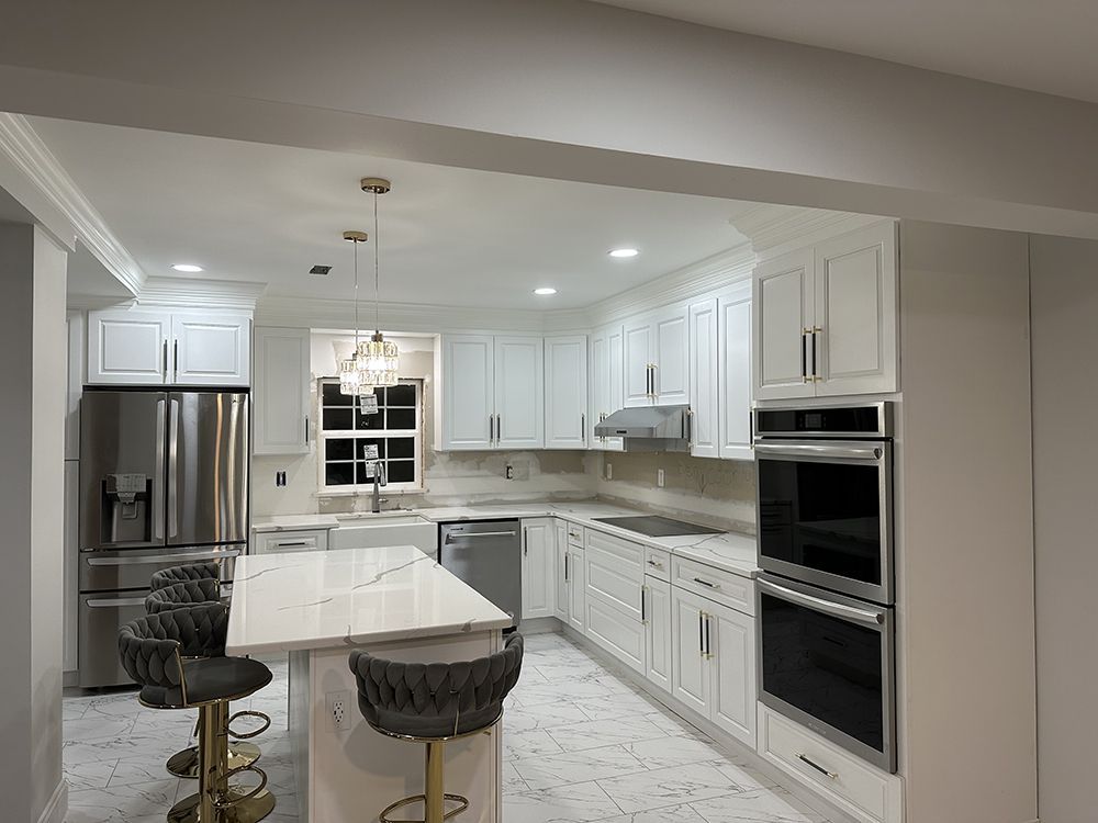 A kitchen with white cabinets, stainless steel appliances, and a large island.