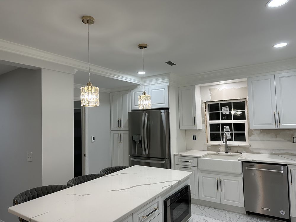 A kitchen with white cabinets, stainless steel appliances, and a large island.
