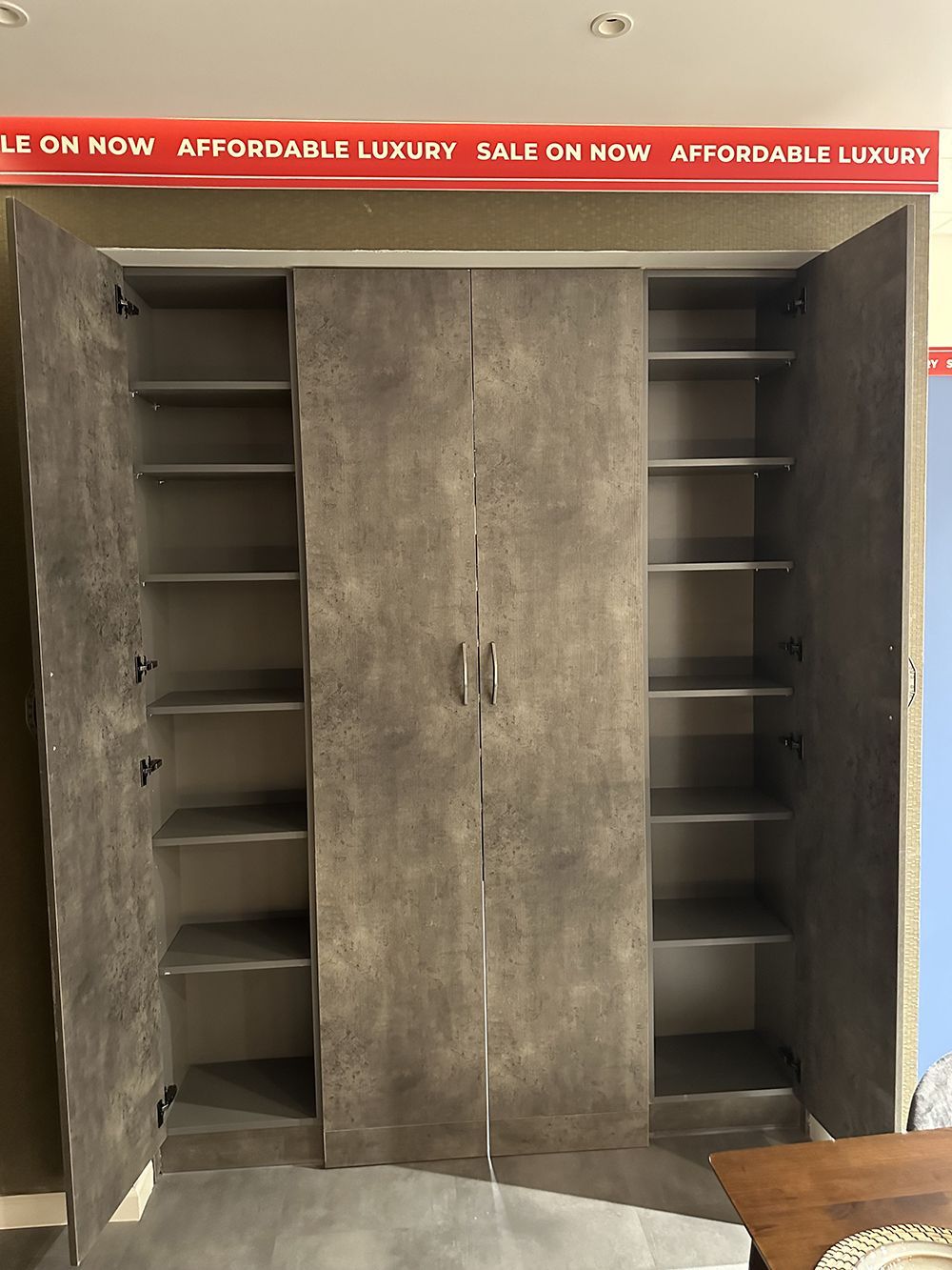 A wardrobe with the doors open and shelves in a room.