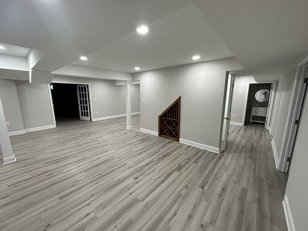 An empty basement with hardwood floors and white walls.
