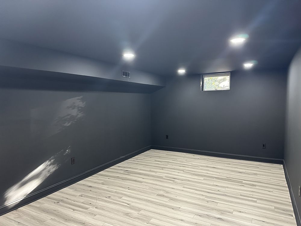 An empty basement with black walls and a wooden floor.