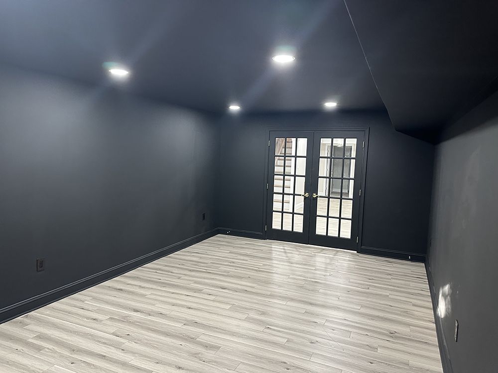 An empty room with black walls and a wooden floor.