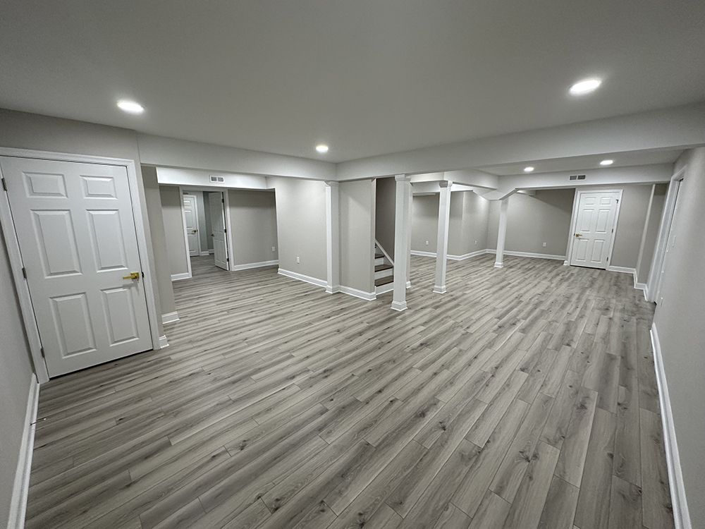 A large empty basement with hardwood floors and white walls.