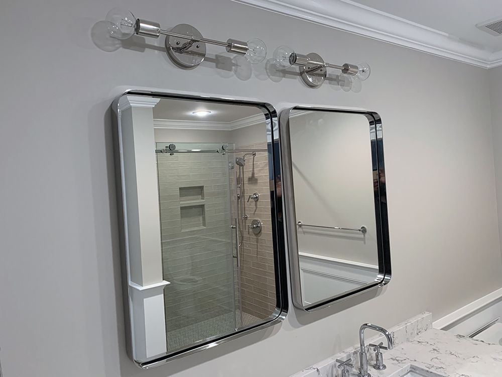 A bathroom with two mirrors and a shower stall.