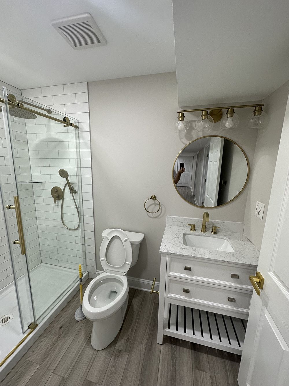 A bathroom with a toilet, sink, shower and mirror.
