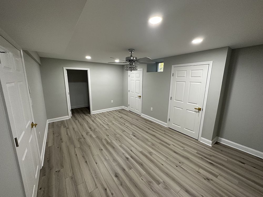 An empty basement with hardwood floors and a ceiling fan.