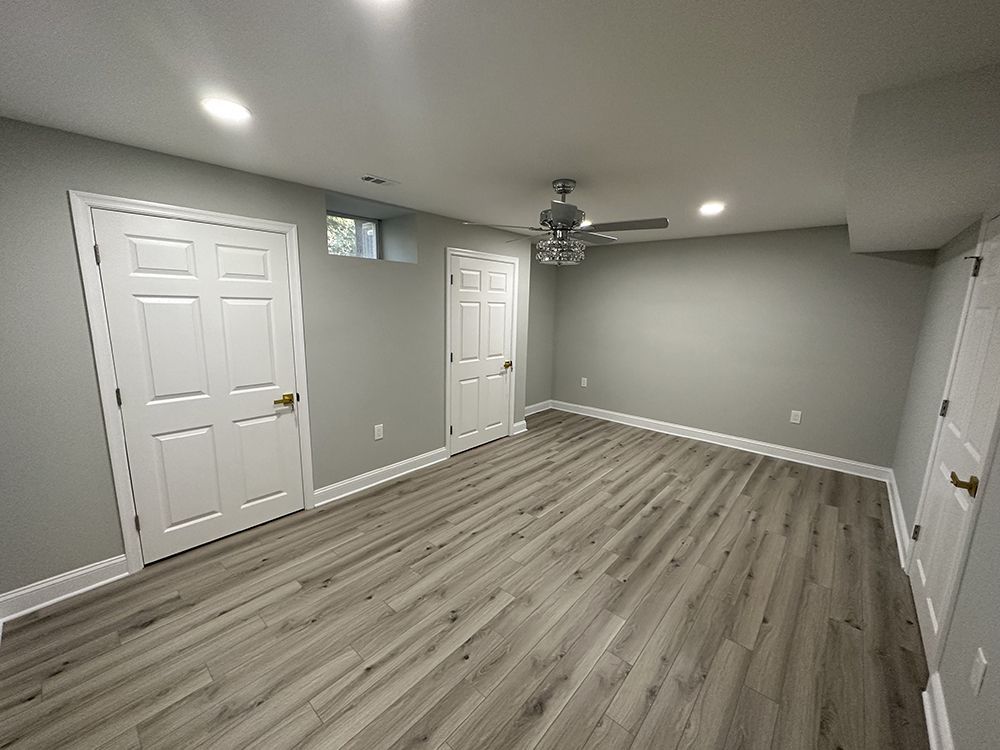 An empty basement with hardwood floors and a ceiling fan.