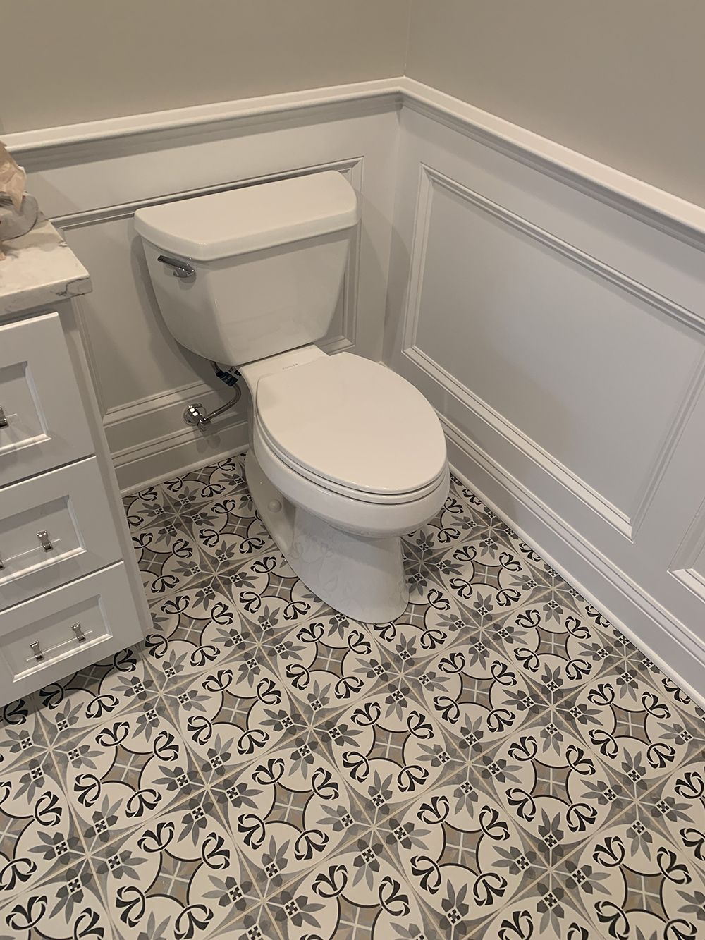 A toilet is sitting on a tiled floor in a bathroom.