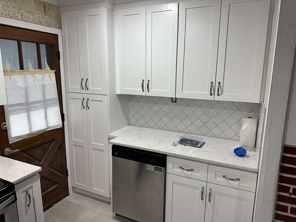 A kitchen with white cabinets and a stainless steel dishwasher.