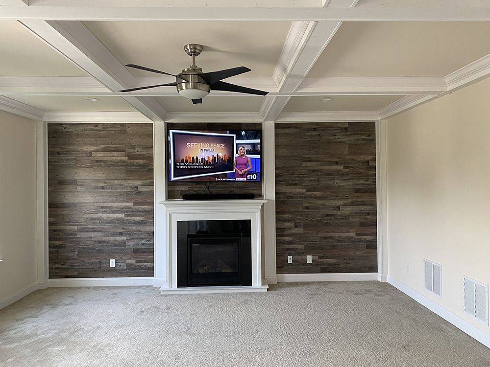 A living room with a fireplace, television and ceiling fan.
