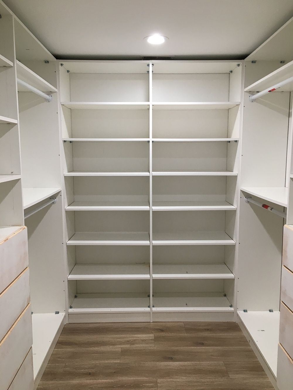 A walk in closet with lots of shelves and drawers.