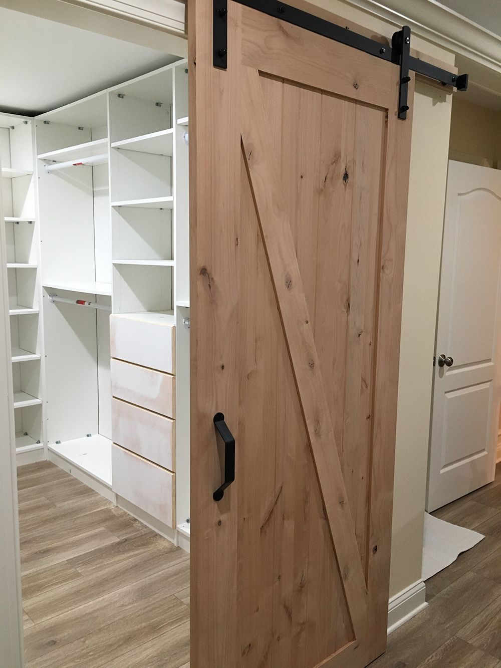 A wooden sliding barn door is open to a walk in closet.
