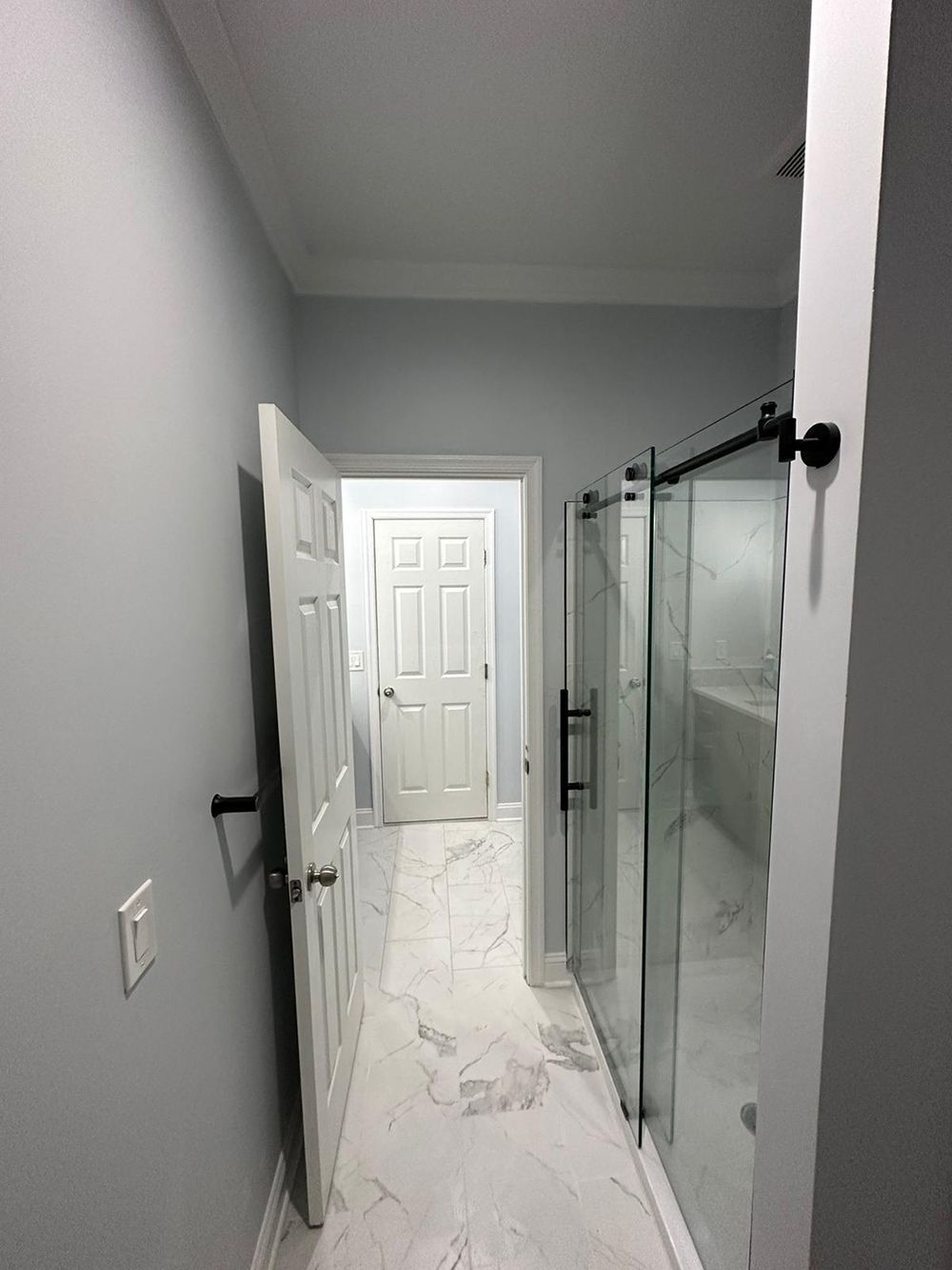 A hallway leading to a bathroom with sliding glass doors.