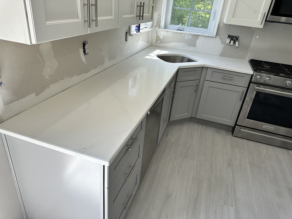 A kitchen with white cabinets , stainless steel appliances , a sink , and a stove.