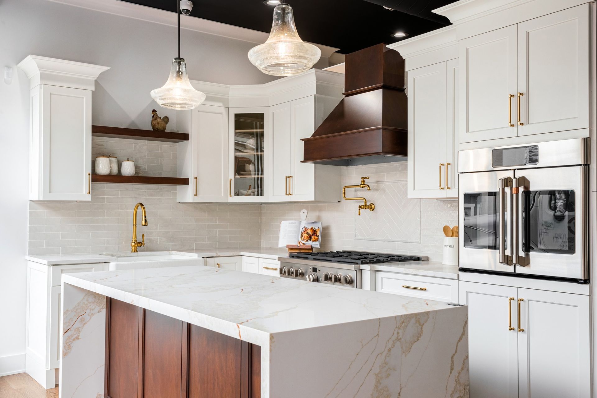 A kitchen with white cabinets , stainless steel appliances , and a large island.