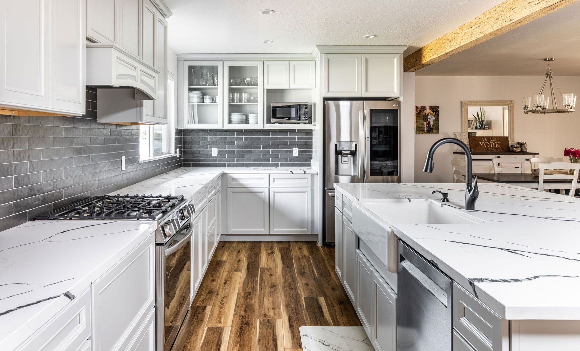 A kitchen with white cabinets , stainless steel appliances , and a large island.