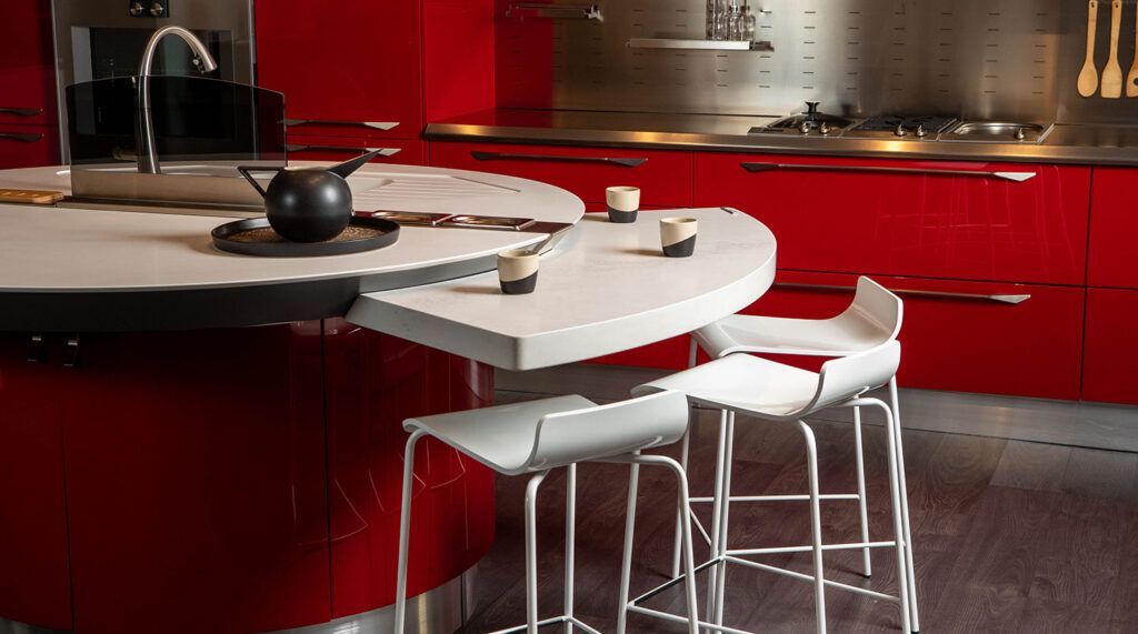 A kitchen with red cabinets and white stools