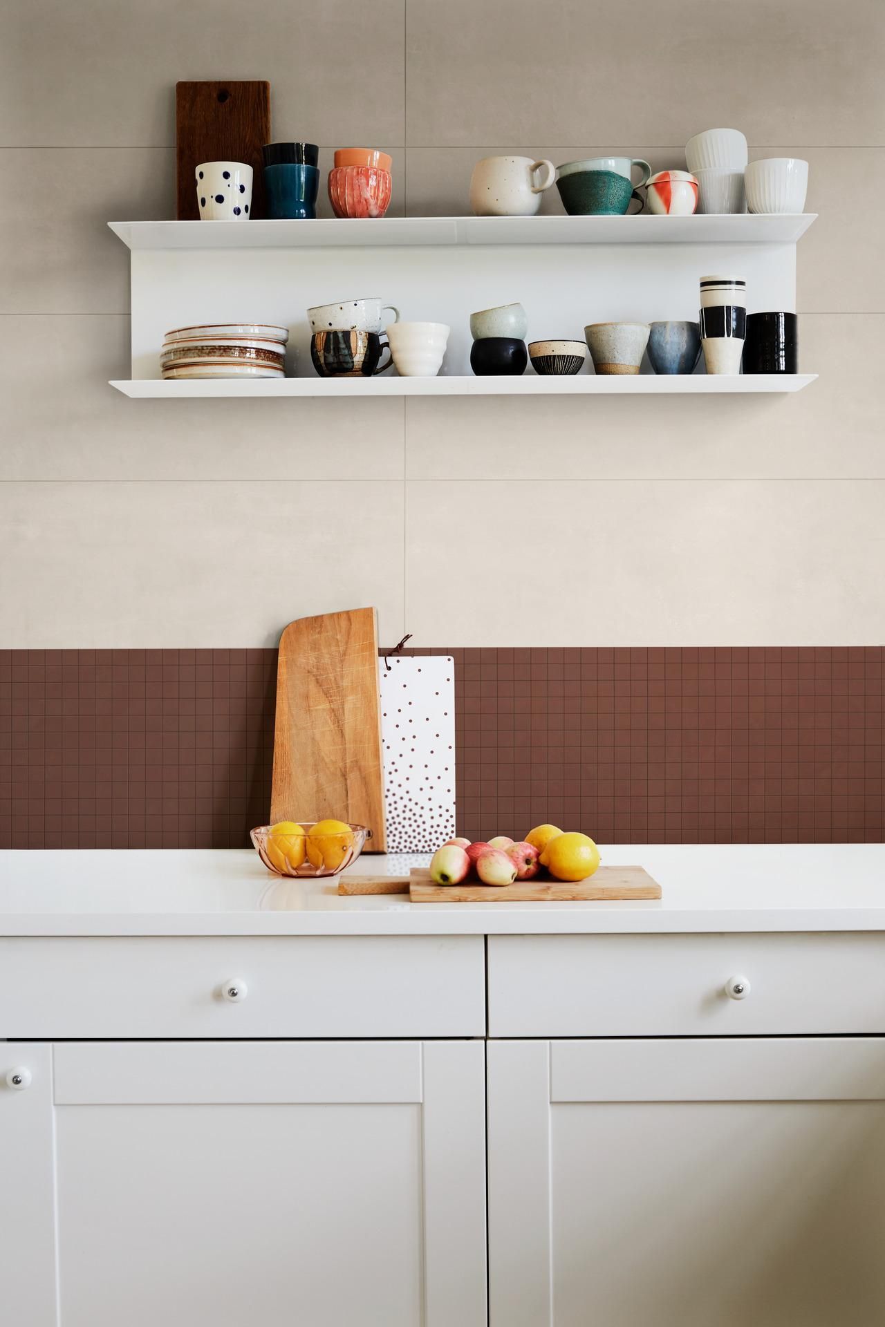 A kitchen with white cabinets and a shelf filled with cups.