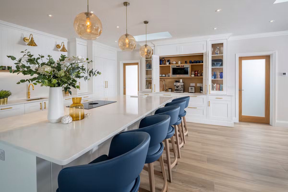 A kitchen with a long island and blue chairs.