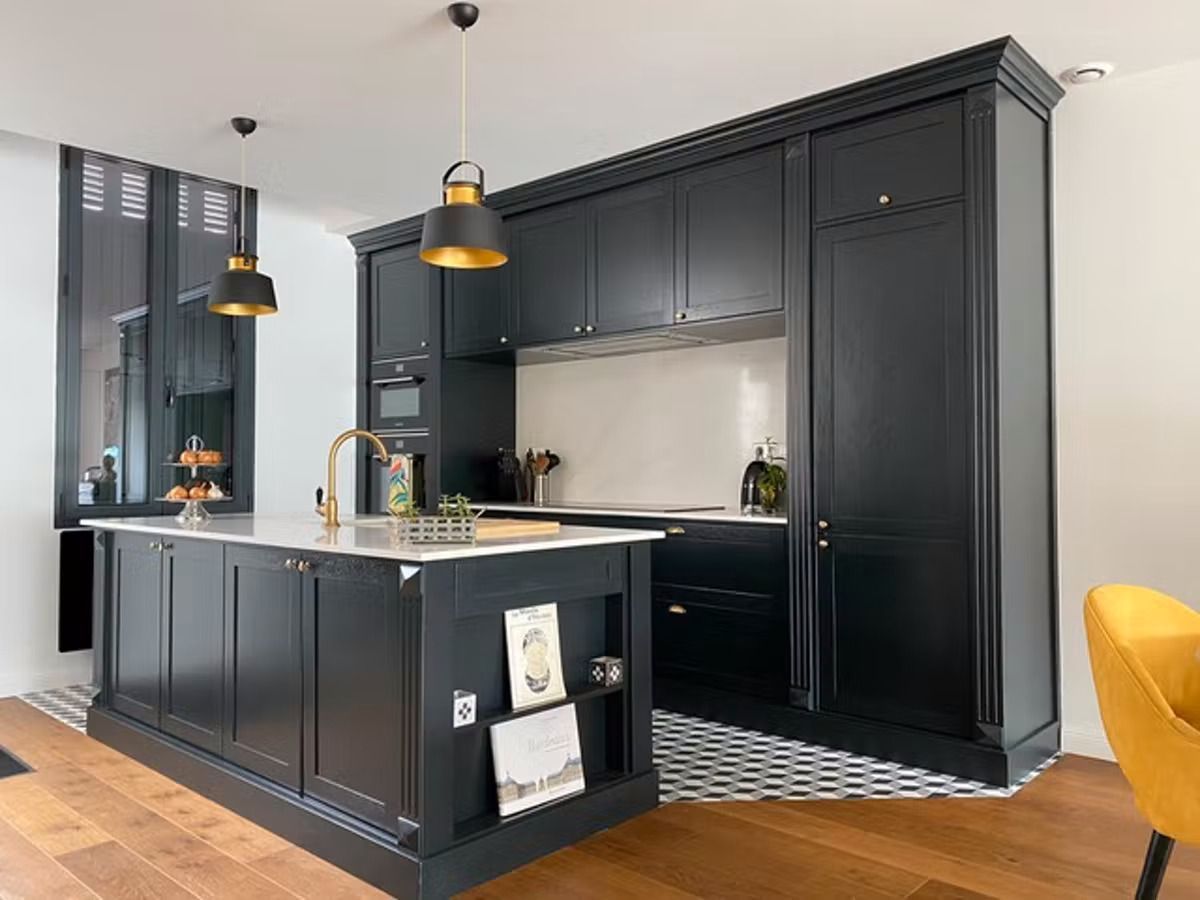 A kitchen with black cabinets and a large island in the middle.
