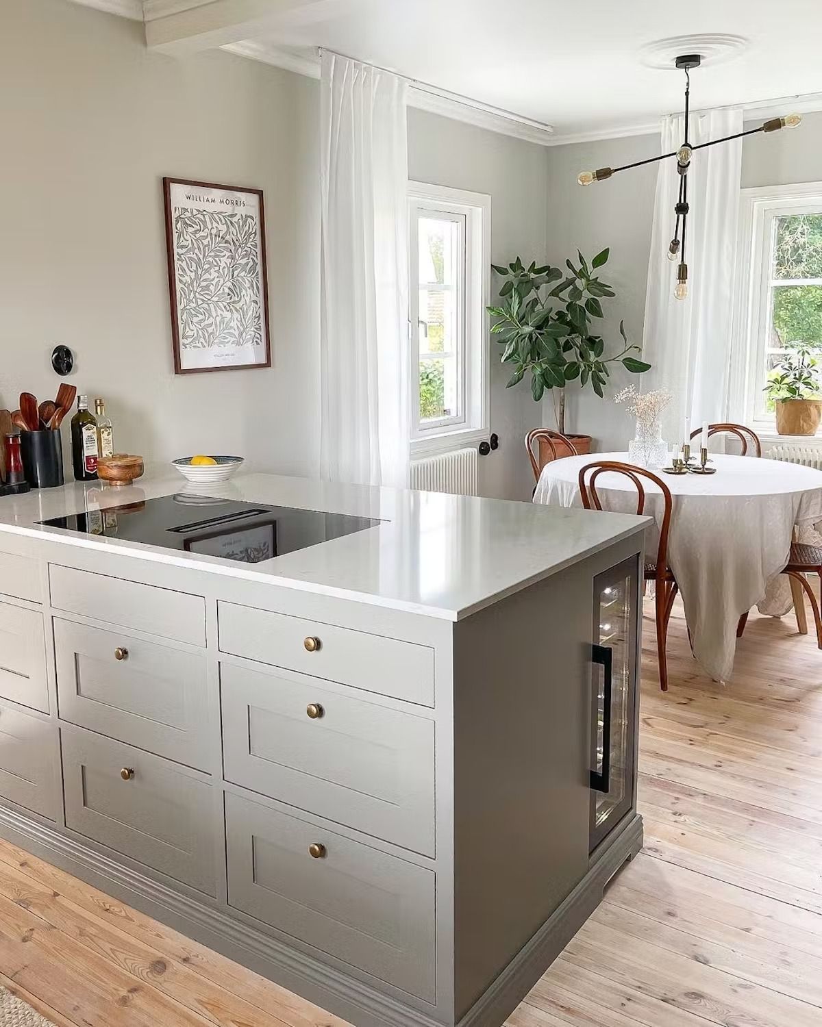 A kitchen with a large island in the middle and a dining room in the background.
