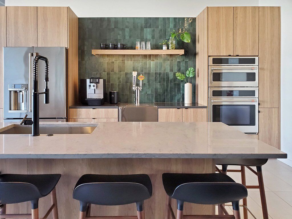 A kitchen with wooden cabinets , stainless steel appliances , a sink , and a large island.