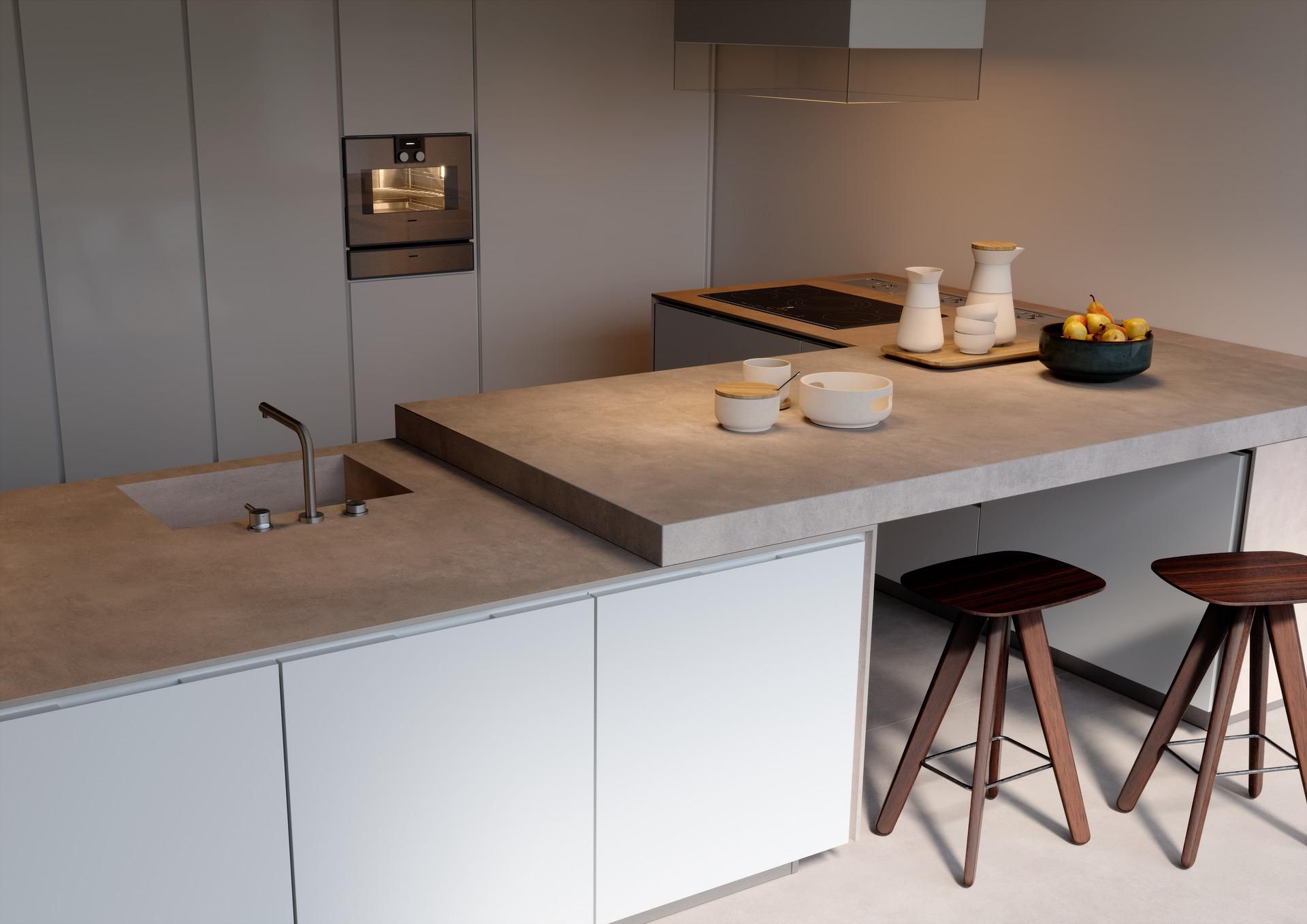 A kitchen with white cabinets and a concrete counter top