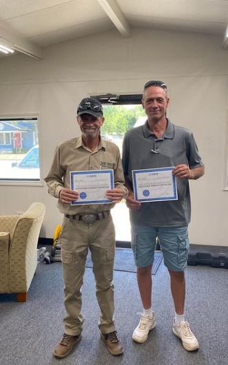 two men holding certificates in a room