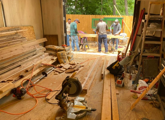 interior workshop with workers cutting wood by a fence