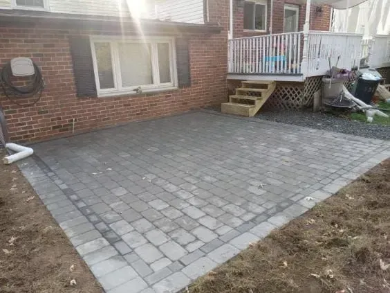 Brick patio next to a brick house and wooden deck.
