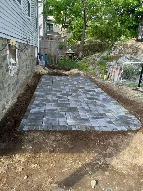 Newly-laid gray paver patio next to a house.