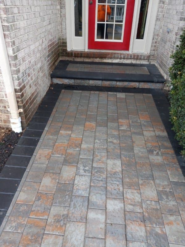 Brick walkway leading to a red door.  Black border surrounds brick steps and pathway.