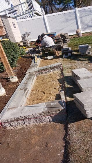 Construction workers building a stone retaining wall in a yard.