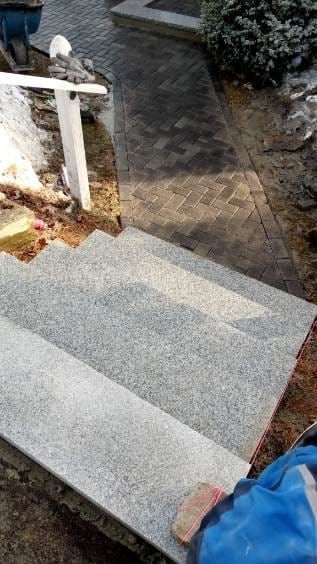 Stone steps leading to a brick path. A person is working on the steps.