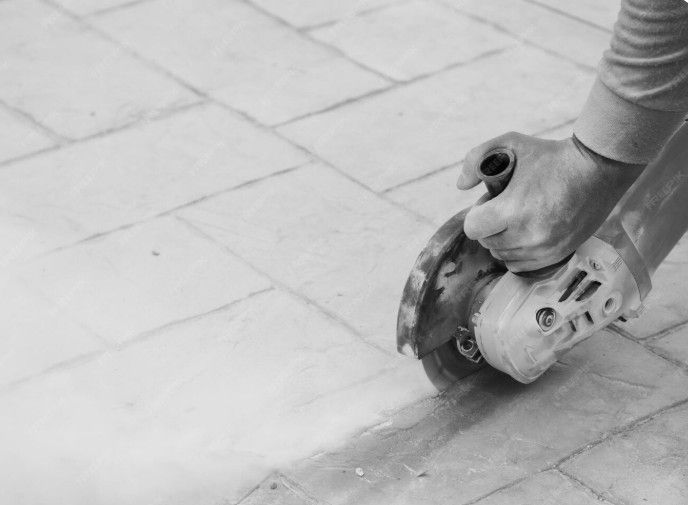 Person using a grinder on paving stones.