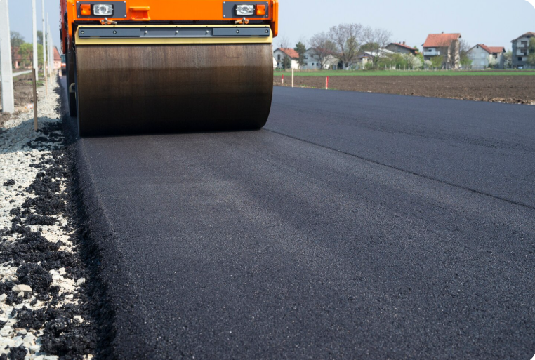 Road roller compacting freshly laid black asphalt on a new road.