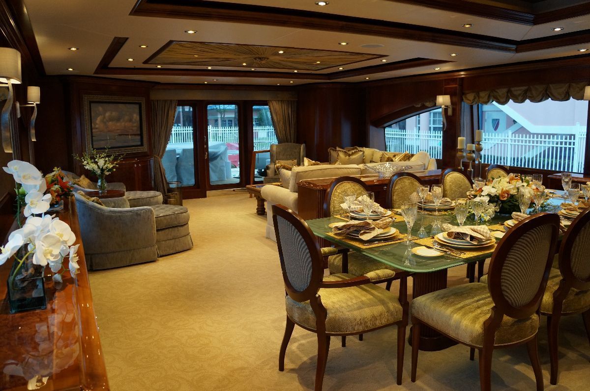 Luxurious yacht interior with dining table, sofas, and large windows.