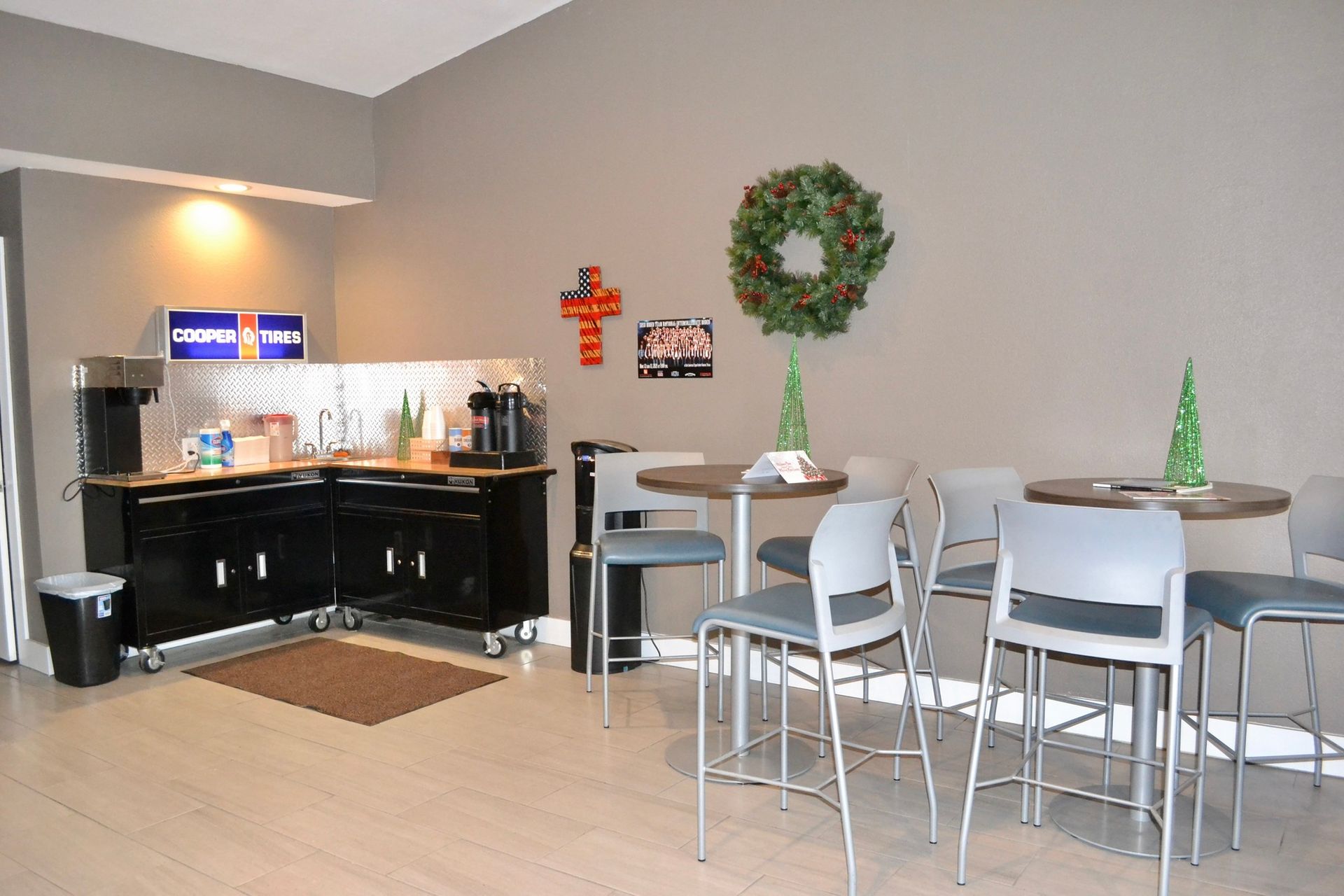 Lounge area with coffee station, round tables, and gray chairs. Christmas wreath and decorations.