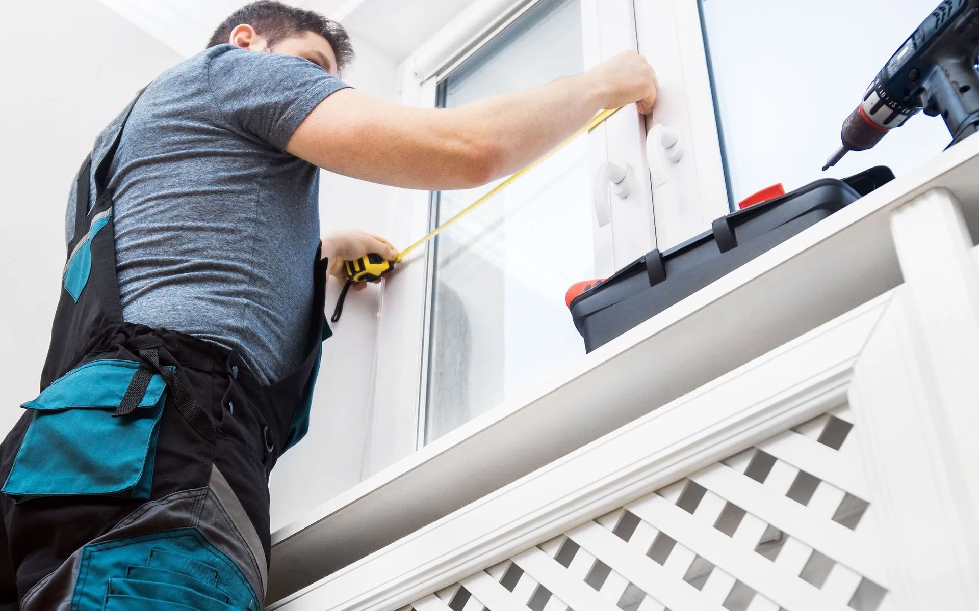 A man is measuring a window with a tape measure.