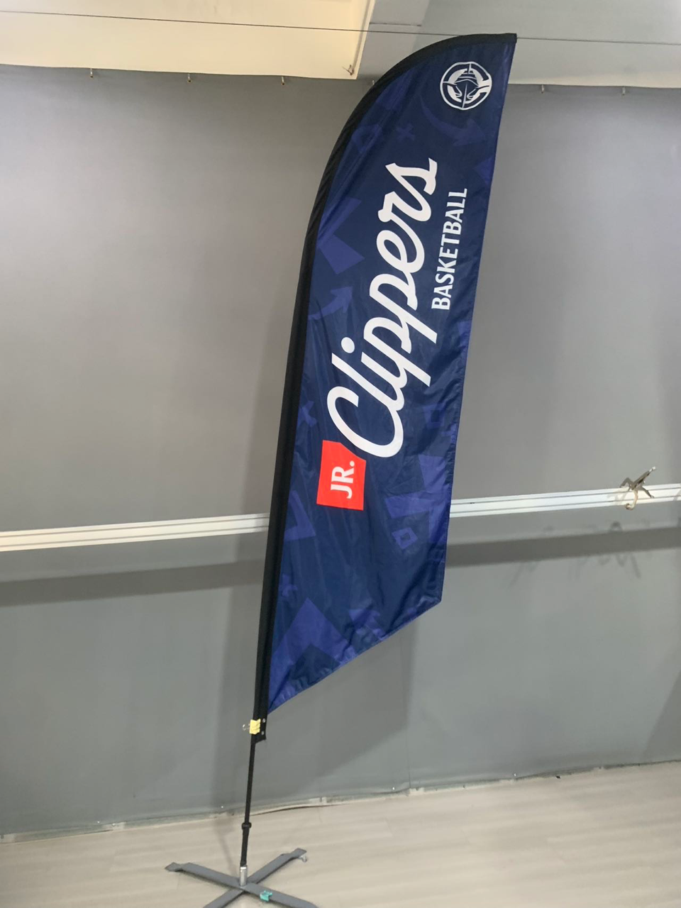The Los Angeles Clippers basketball team's feather flag is indoors. Blue with white lettering, logo on top.