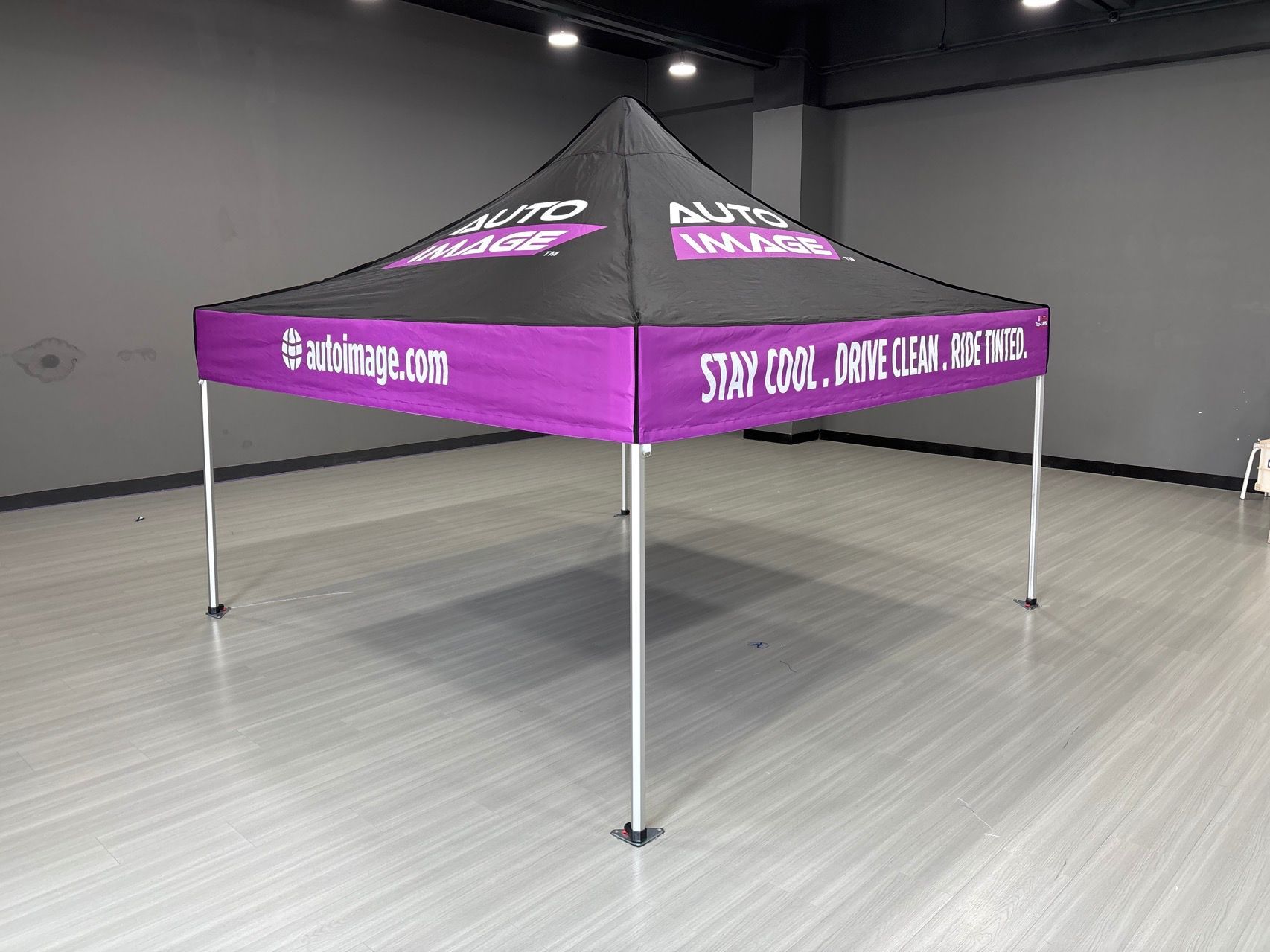 A purple and black canopy tent with company logos, set up on a gray floor.