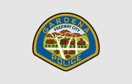Gardena Police Department badge featuring city buildings and mountains, with blue, gold, and green colors.